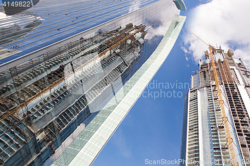 Image of Skyscrappers construction site with cranes on top of buildings.