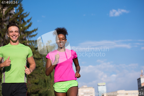 Image of young smiling multiethnic couple jogging in the city