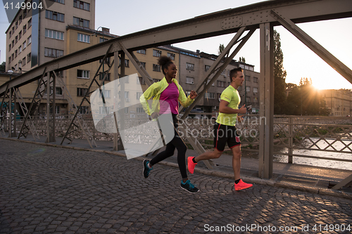 Image of young multiethnic couple jogging in the city