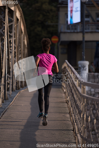 Image of african american woman running across the bridge