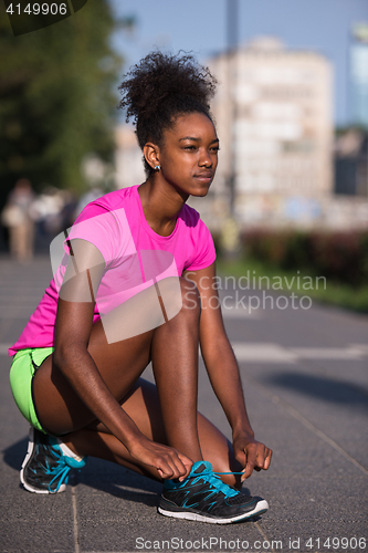 Image of African american woman runner tightening shoe lace