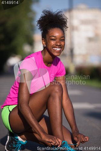 Image of African american woman runner tightening shoe lace
