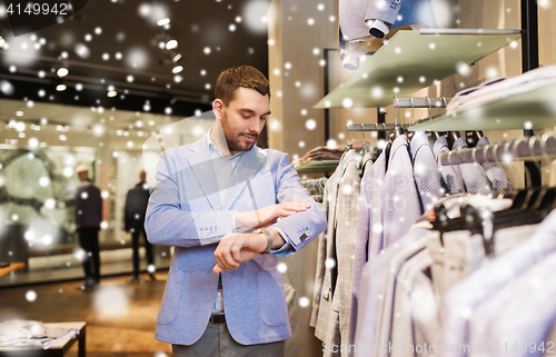 Image of happy young man trying jacket on in clothing store