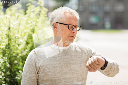 Image of senior man checking time on his wristwatch