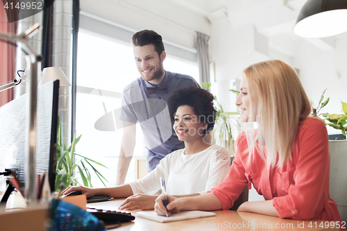 Image of happy creative team with computer in office