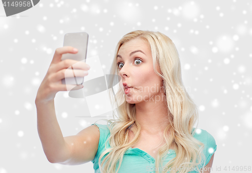 Image of funny young woman taking selfie with smartphone