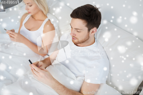 Image of couple with smartphones in bed