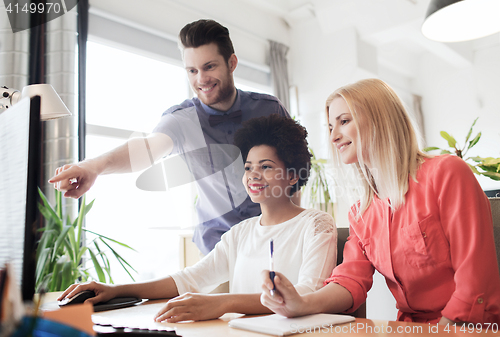 Image of happy creative team with computer in office