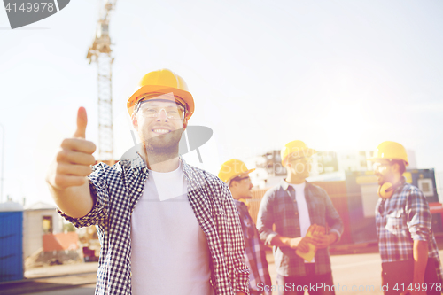 Image of group of smiling builders in hardhats outdoors