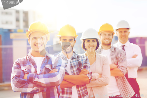 Image of group of smiling builders in hardhats outdoors