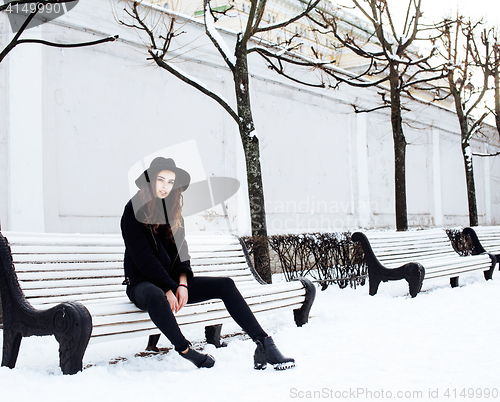 Image of young pretty modern hipster girl waiting on bench at winter snow park alone, lifestyle people concept