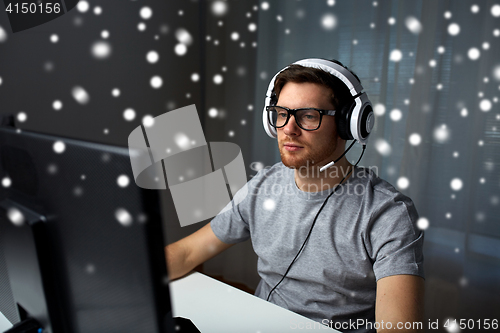 Image of man in headset playing computer video game at home