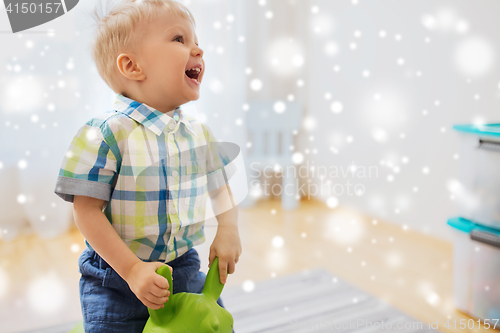 Image of happy baby boy playing with ride-on toy at home