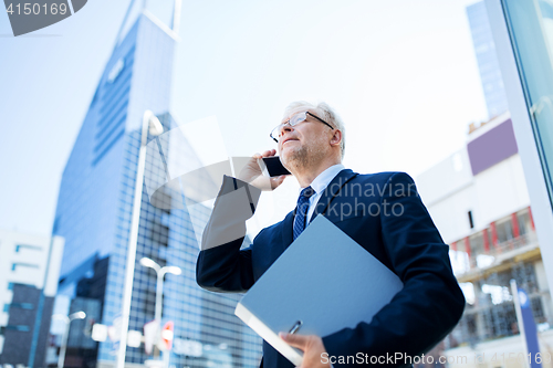 Image of senior businessman calling on smartphone in city