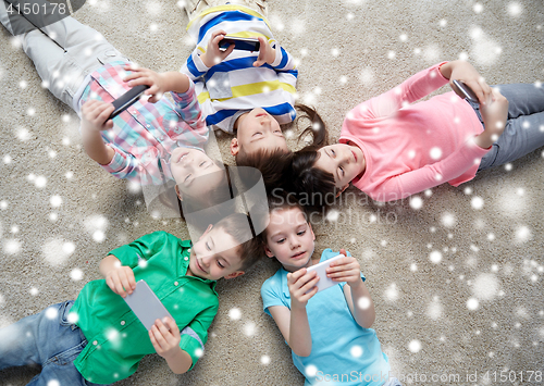 Image of happy children with smartphones lying on floor