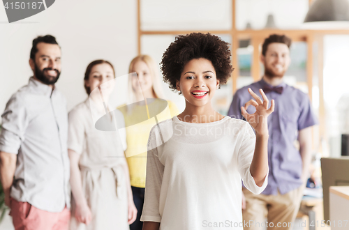 Image of happy woman showing ok over creative office team