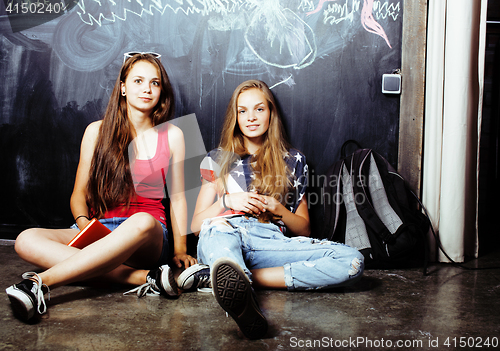 Image of back to school after summer vacations, two teen real girls in classroom with blackboard painted together