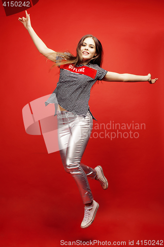 Image of young pretty emitonal posing teenage girl on bright red background jumping with flying hair, happy smiling lifestyle people concept