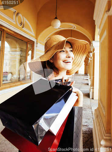 Image of young pretty smiling woman in hat with bags on shopping at store