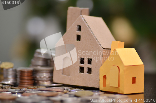 Image of Paper house and stacks of coins standing