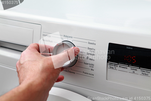 Image of man hand switches on washing machine