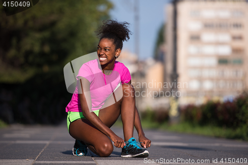 Image of African american woman runner tightening shoe lace