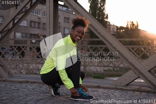 Image of African american woman runner tightening shoe lace