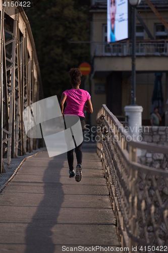 Image of african american woman running across the bridge