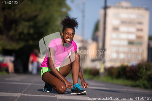 Image of African american woman runner tightening shoe lace