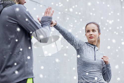 Image of woman with coach working out strike outdoors