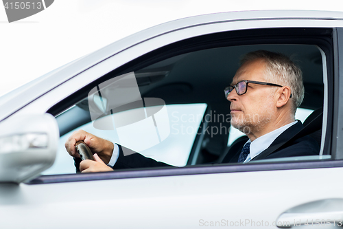 Image of happy senior businessman driving car