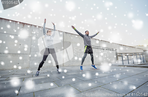 Image of happy man and woman jumping outdoors