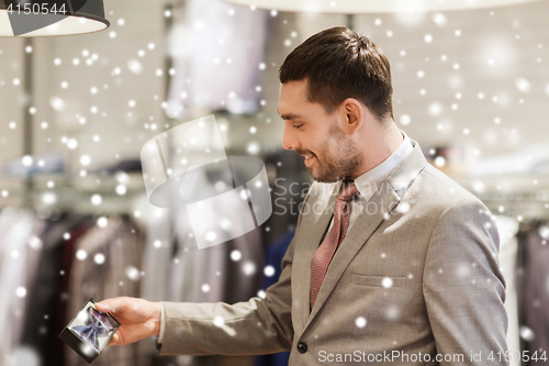 Image of happy young man choosing bow-tie in clothing store