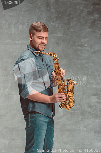 Image of Happy saxophonist with sax over gray background