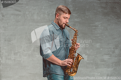 Image of Happy saxophonist playing music on sax over gray background