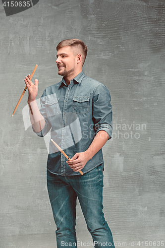 Image of Man holding two drumsticks over gray background