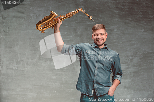 Image of Happy saxophonist with sax over gray background