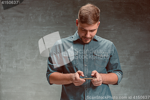 Image of The young smiling caucasian businessman on gray background with phone
