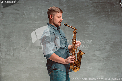 Image of Happy saxophonist with sax over gray background