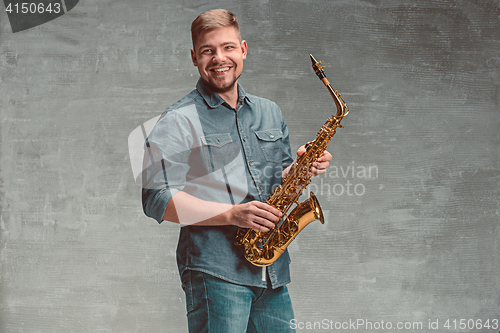 Image of Happy saxophonist with sax over gray background