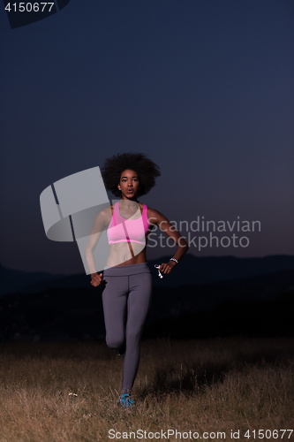 Image of Young African american woman jogging in nature