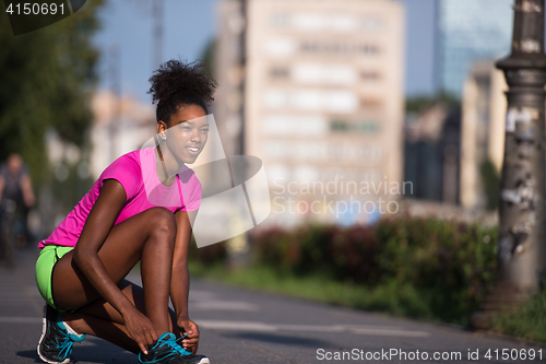 Image of African american woman runner tightening shoe lace