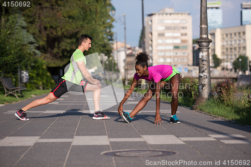 Image of jogging couple warming up and stretching in the city