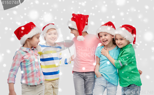 Image of happy little children in santa hats hugging