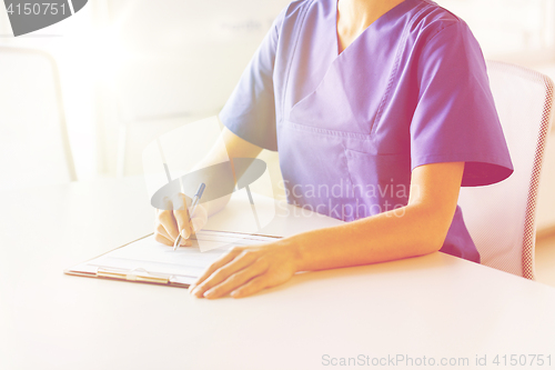 Image of close up of doctor or nurse writing to clipboard
