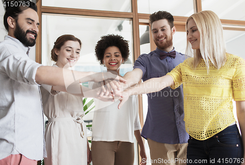 Image of happy creative team ith hands on top in office