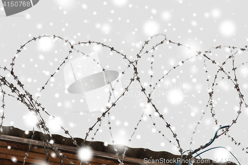 Image of barb wire fence over gray sky and snow