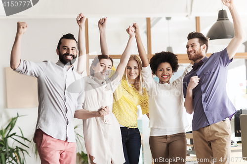 Image of happy creative team celebrating victory in office