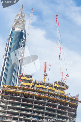 Image of Skyscrappers construction site with cranes on top of buildings.