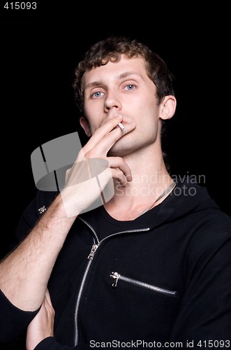 Image of The young man smokes a cigarette. Isolated on a black background